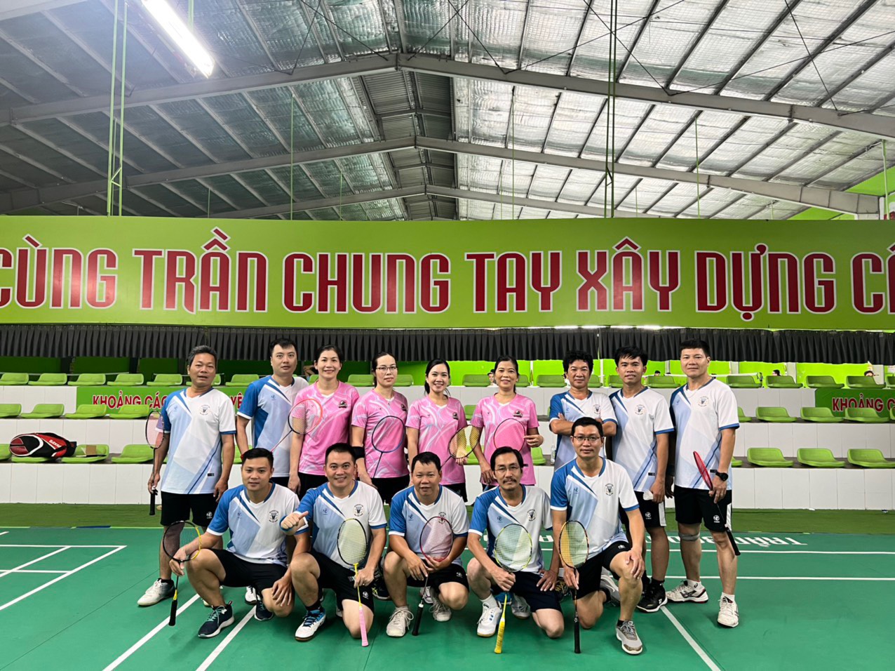 CLB cầu lông nữ mặc áo đồng phục chụp ảnh tại sân thi đấu